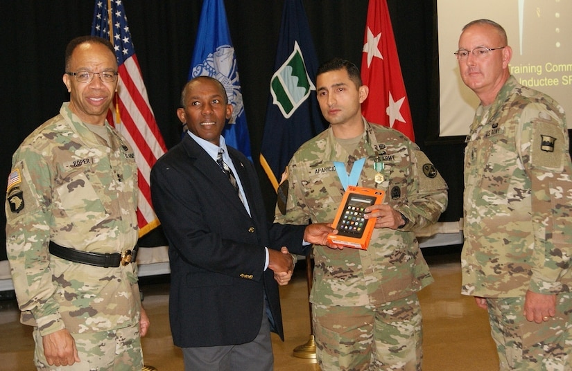 Retired Sgt. Maj. Gary Lyons (second from left) presents Sgt. 1st Class Daniel Aparicio with a Kindle Fire tablet as a gift at Aparicio's Sgt. Audie Murphy Club induction ceremony held at Fort Devens, Massachusetts, April 6, 2017. Maj. Gen. A.C. Roper (left), commander of the 80th Training Command, and Command Sgt. Maj. Jeffrey Darlington (right), 80th TC senior enlisted leader, pose for pictures with Lyons and Aparicio.