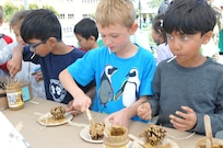 Students from a local elementary school creates bird feeders with pine cones, peanut butter and bird seeds at an Earth Day booth facilitated by the 63rd Regional Support Command Department of Public Works Environmental Team.