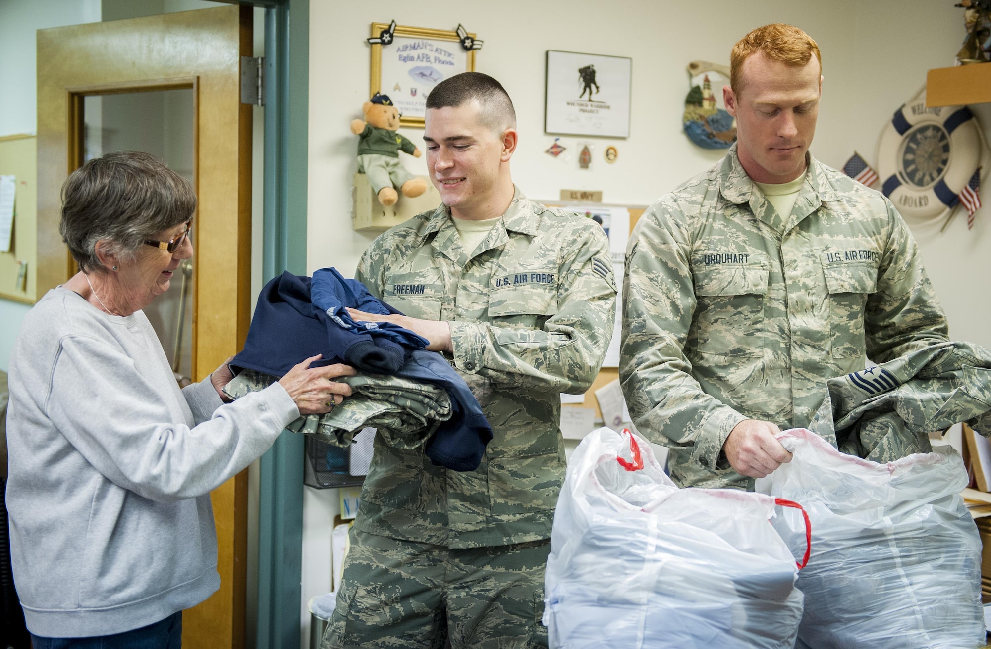 Senior Airman Skylar Freeman (center) and Airman 1st Class Jeffrey Urquhart, from the 96th Logistics Readiness Squadron, hand donated uniform items to Fran Moore, an Airman's Attic volunteer, during Volunteer Week, observed April 24 -28 at Eglin Air Force Base, Fla.  The Airmen volunteered a few hours at the Airman’s Attic for service members in need.  (U.S. Air Force photo/Kevin Gaddie)