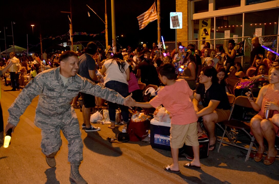 Senior Master Sgt. Richard Sanchez, a 433rd Maintenance Squadron supervisor in the Aerospace Ground Equipment shop, low-fives a fan during the 69th annual Fiesta Flambeau Parade, April 29, 2017. Sanchez was escorting the 433rd Airlift Wing's “City Lights and Celebrations” themed float was seen by over 700,000 spectators lining the 2.6 mile long route on the downtown streets of San Antonio. (U.S. Air Force Photo/ Tech. Sgt. Carlos J. Trevino)