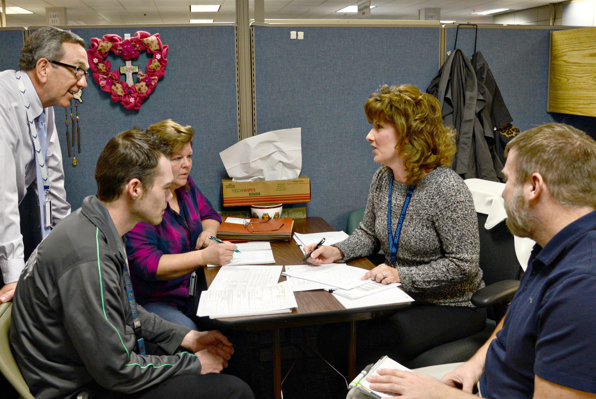 448th Supply Chain Management Wing Director Frank Washburn, looks in on a meeting between, from left, Jacob Franzoni, Kathy Hubbard, Bobbie Knoch and Tim Eldridge, all with the 421st Supply Chain Management Squadron’s F100 engine office. (Air Force photo by Kelly White)