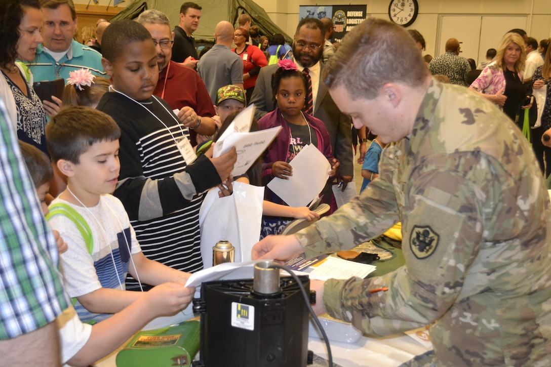 Army Lt. Col. Paul McCullough, Construction and Equipment supply chain program manager for audit readiness, places stickers on children’s scavenger hunt worksheets in the DLA Troop Support Bldg. 6 auditorium as part of Take Our Daughters and Sons to Work Day April 27, 2017. More than 440 children participated in interactive activities to learn more about the missions of DLA Troop Support and NAVSUP Weapon Systems Support.