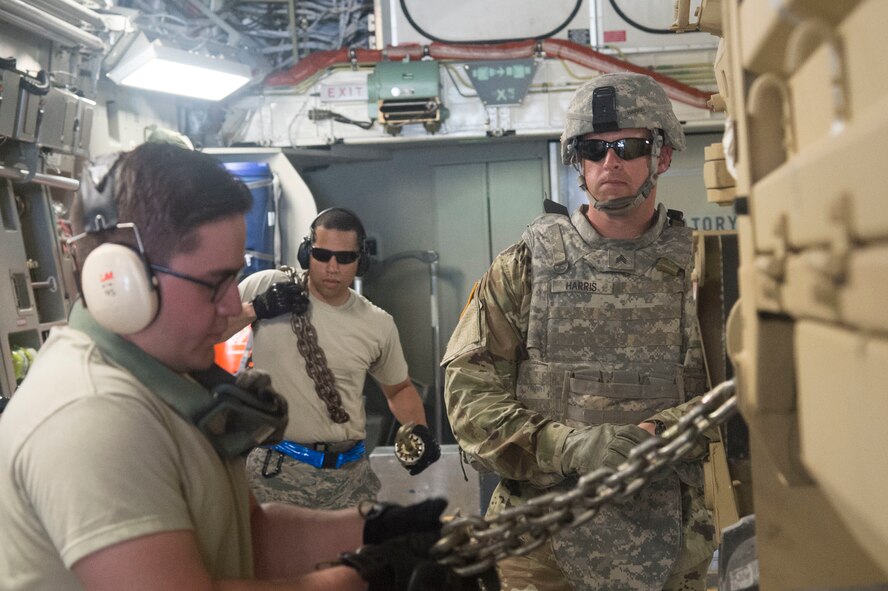 Airman First Class Giovanni Jaramillo (left) and Senior AirmanTerrance Daniels (middle), aircraft services specialists with the 621st Contingency Response Group stationed at Joint Base McGuire-Dix-Lakehurst in New Jersey, strap down a vehicle from the U.S. Army 1st Infantry Division, from Fort Riley, Kansas during joint exercise Cerberus Strike 17-01 at Savage Army Airfield on April 18, 2017. The joint exercise allows members the opportunity to rehearse potential real-world situations, including in cargo uploading and downloading on aircraft.(U.S. Air Force photo by Staff Sgt. Robert Waggoner/RELEASED)