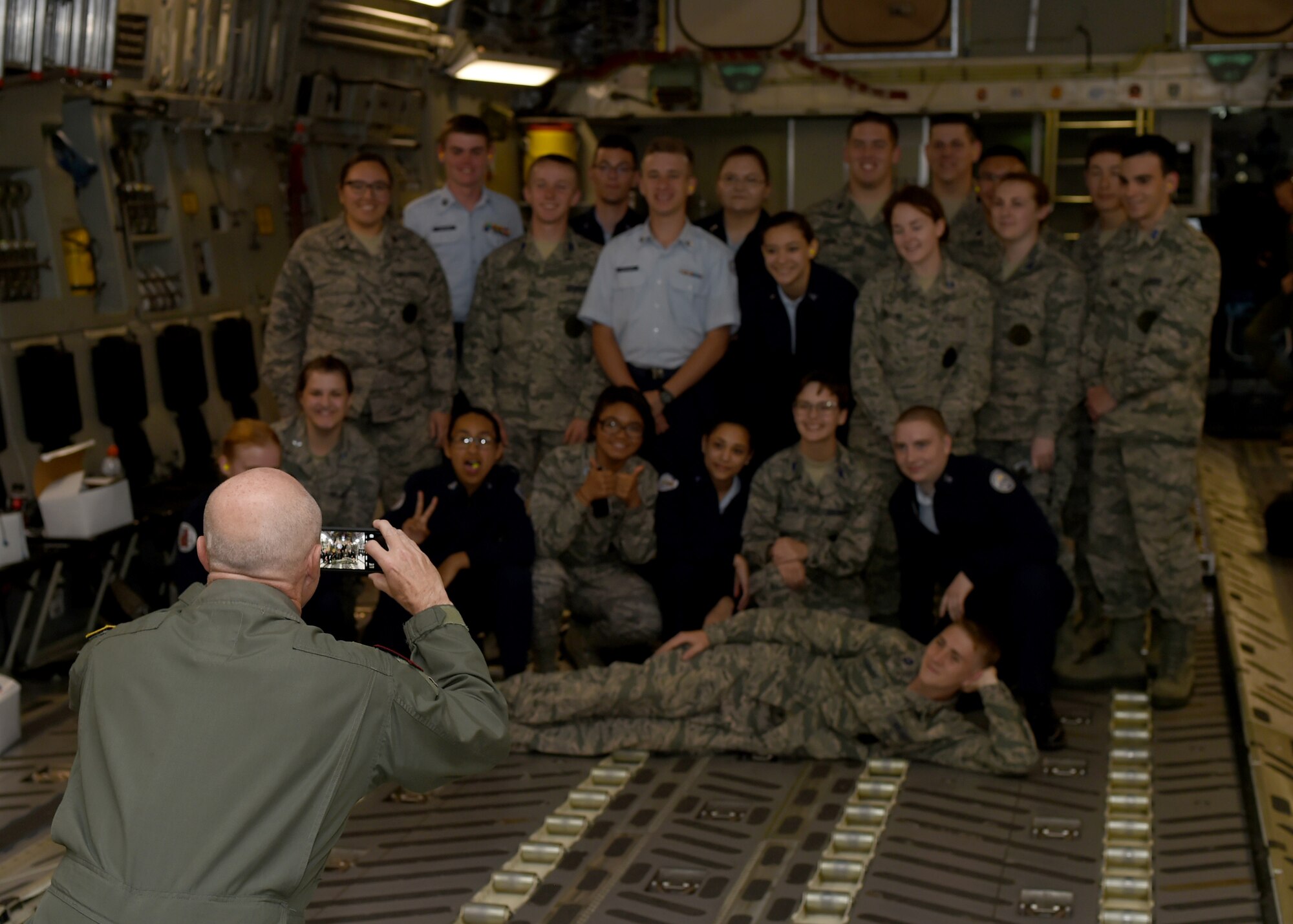 Retired U.S. Air Force Lt. Col. Bob West, Denton High School’s senior aerospace science instructor, takes a photo of his Air Force Junior ROTC cadets aboard a U.S. Air Force C-17 Globemaster III cargo aircraft, April 26, 2017. The 24 cadets learned about the important roles the C-17 and its crew play in the Air Force. (U.S. Air Force photo by Airman 1st Class Kirby Turbak/Released)
