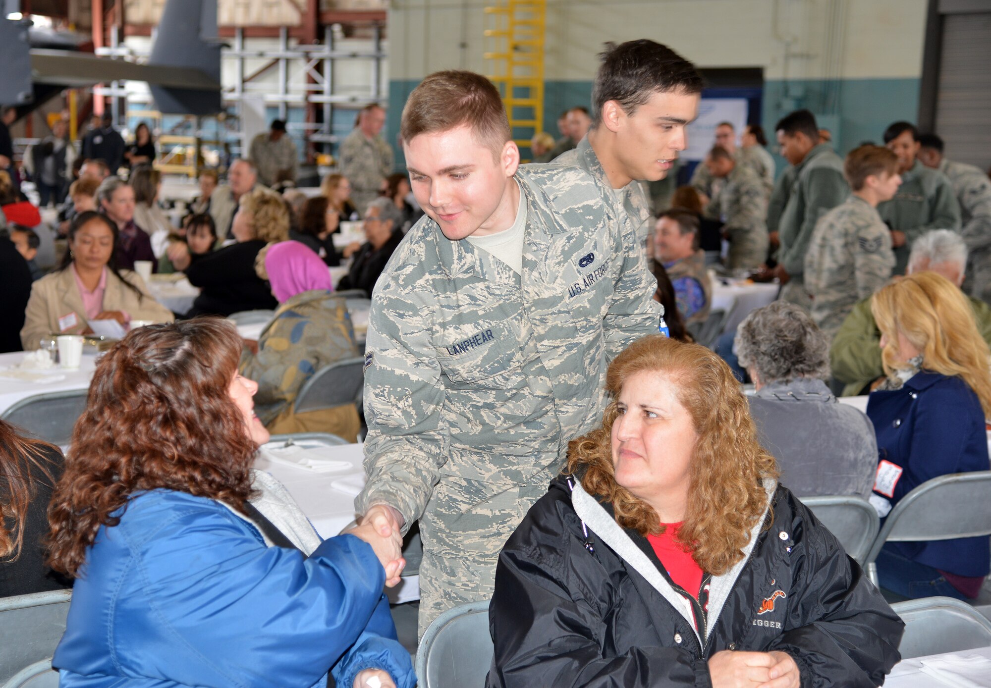 Airman 1st Class Shawn Lanphear, 58th Maintenance Group, presents a commerorative coin to guest Sheryl McGartland as Aurora Garcia looks on. The coining concluded the Warriors to Warriors event, conducted to raise awareness and encourage people in the fight against Ovarian Cancer April 29 at Hanagar 1000. 