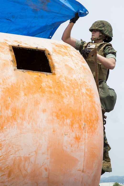U.S. Marine Corps Lance Cpl. Jacqueline Radzick, a heavy equipment operator with Marine Wing Support Squadron (MWSS) 171, covers a tank with a tarp during a simulated aircraft crash for exercise Tanuki Wrath at Marine Corps Air Station Iwakuni, Japan, April 27, 2017. During the exercise Marines with MWSS- 171 recovered a tank that represented a simulated aircraft. The exercise keeps Marines prepared to react appropriately in the case of an aircraft crash. (U.S. Marine Corps photo by Pfc. Mason Roy)