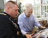 Maj. Gen. Troy D. Kok, commanding general of the U.S. Army Reserve’s 99th Regional Support Command, presents framed artwork from World War II to Claude Hodges, a 99th Infantry Division veteran who served during the Battle of the Bulge and is currently a resident at the Virginia Veterans Care Center in Roanoke, Virginia. Kok visited Hodges and other veterans at the center April 28.