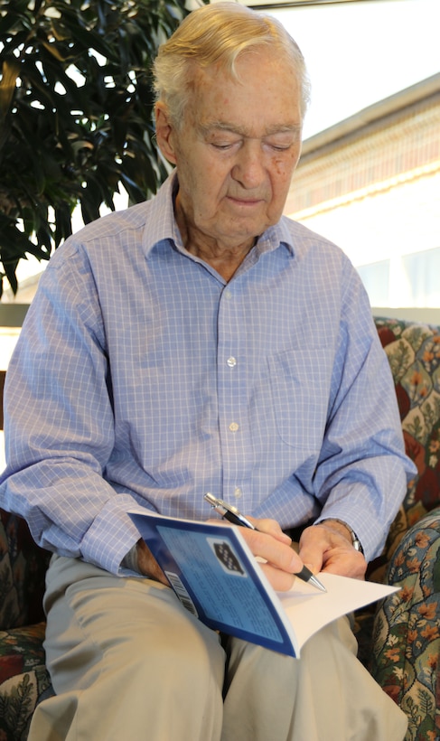 Claude Hodges, a 99th Infantry Division veteran who served during the Battle of the Bulge and is currently a resident at the Virginia Veterans Care Center in Roanoke, Virginia, autographs a copy of, “Battle Baby at the Bulge: The POW Experience of Claude Hodges,” by Col. Greg Eanes. Maj. Gen. Troy D. Kok, commanding general of the U.S. Army Reserve’s 99th Regional Support Command, visited Hodges and other veterans at the center April 28.