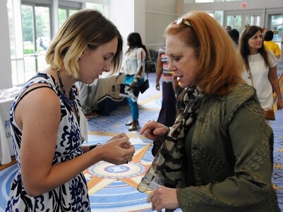 Spc. Kristen Draheim (left), a nodal network systems operator-maintainer from Summerville, South Carolina currently assigned to the U.S. Army Reserve’s 392nd Expeditionary Signal Battalion, gets contact information April 29 from Lettie J. Bien, Army Reserve Ambassador for the Commonwealth of Virginia.  Bien was among the speakers during the opening session of a Yellow Ribbon Reintegration Program event at Oxon Hill, Maryland.  The YRRP is a congressionally mandated program that helps service members and their families connect with their local support community before, during and after deployments.