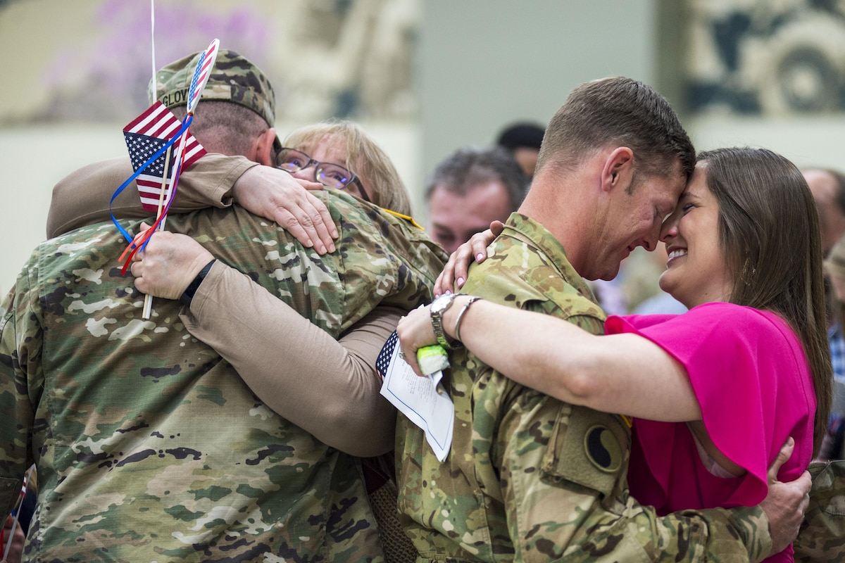 Two soldiers embrace loved ones as they return from deployment.