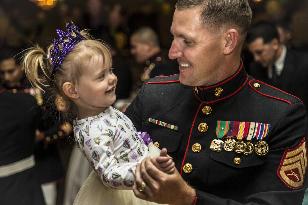 A Marine dances with his 2-year-old daughter at an event.