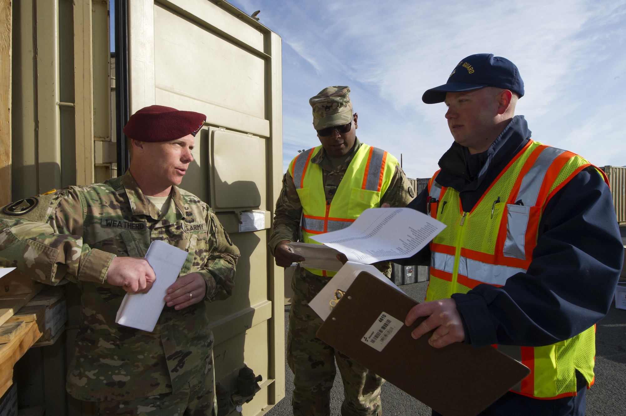 U.S. Coast Guard Marine Science Technician Petty Officer 1st Class Gary Bullock, right, and Army Staff Sgt. Luis Ramos, center, talk to a Soldier while inspecting a container for any undeclared hazmat materials before it is shipped to Fort Polk, Louisiana from Joint Base Elmendorf-Richardson, Alaska, May 2, 2017. The 4th Brigade Combat Team (Airborne), 25th Infantry Division will conduct a rotation at the Joint Readiness Training Center at Fort Polk. Bullock is assigned to the Coast Guard Marine Safety Detachment Homer and Ramos is assigned to the 842nd Transportation Battalion, 597th Transportation Brigade, Beaumont, Texas. (U.S. Air Force photo by Staff Sgt. Sheila deVera)

