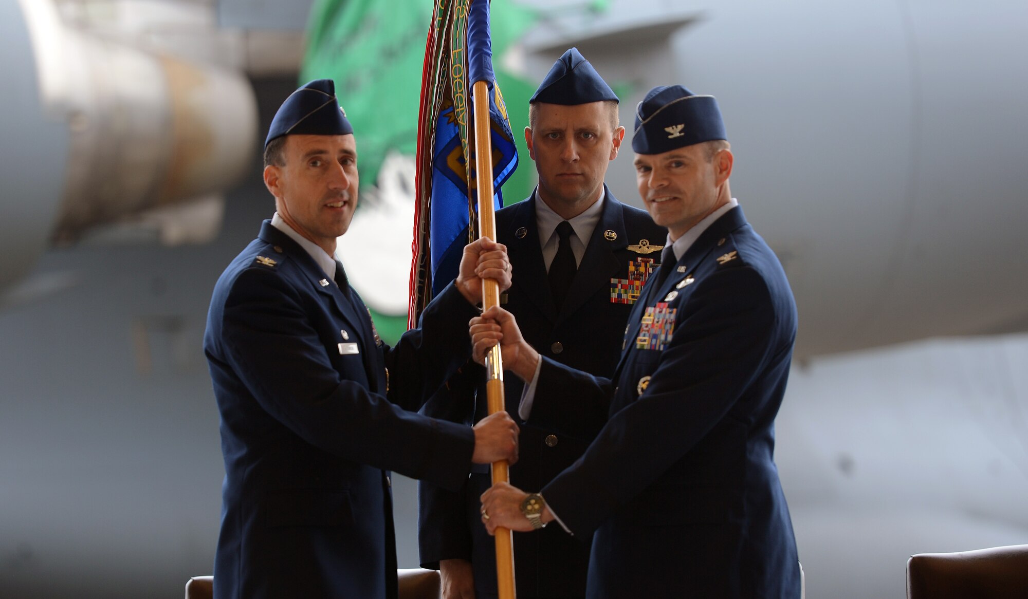 Col. Leonard Kosinski (left), passes a guidon to Col. Mark Fuhrmann, 62nd Operations Group commander, as Chief Master Sgt. Scott Mills (center), 62nd OG chief, stands at attention May 1, 2017, during a change of command ceremony at Joint Base Lewis-McChord, Wash.  Fuhrman took command from the outgoing commander Lt. Col. Brian Smith. (U.S. Air Force photo/Senior Airman Jacob Jimenez) 