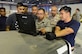Qatari air force representatives look on as U.S. Air Force Master Sgt. Nino Lucena, Air Freight Superintendent assigned to the 8th Expeditionary Air Mobility Squadron, reviews pallet loading training orders on a lap top computer. The group is taking part in the first of many collaborative training exercises between U.S. Air Force and Qatari air force personnel. (U.S. Air Force photo by Tech. Sgt. Bradly A. Schneider)