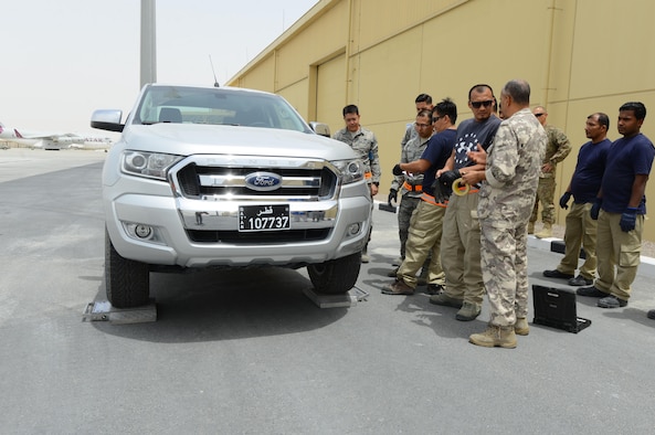 U.S. Air Force and Qatari air force personnel gather around a vehicle outside a newly constructed facility located at Al Udeid Air Base, Qatar, April 26, 2017. The personnel are taking part in the first of many opportunities to train on how to properly collect information necessary to determine the total weight and center of gravity for equipment to be loaded for transportation on aircraft. (U.S. Air Force photo by Tech. Sgt. Bradly A. Schneider)