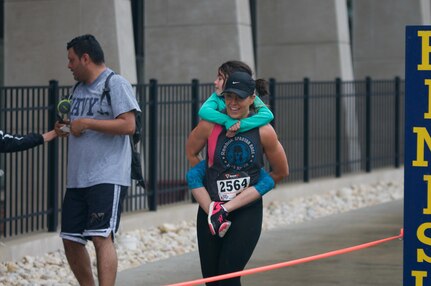 Stephanie Casado, temporary coordinator of the Veterans Affairs department at Kutztown University, carries her daughter Maya across the finish line at the fourth annual Keystone Warrior 5k Run/Walk at Kutztown University. The event, which serves as MCKU's primary fundraiser, directs up to 98 percent of proceeds to wounded veterans in Pennsylvania.