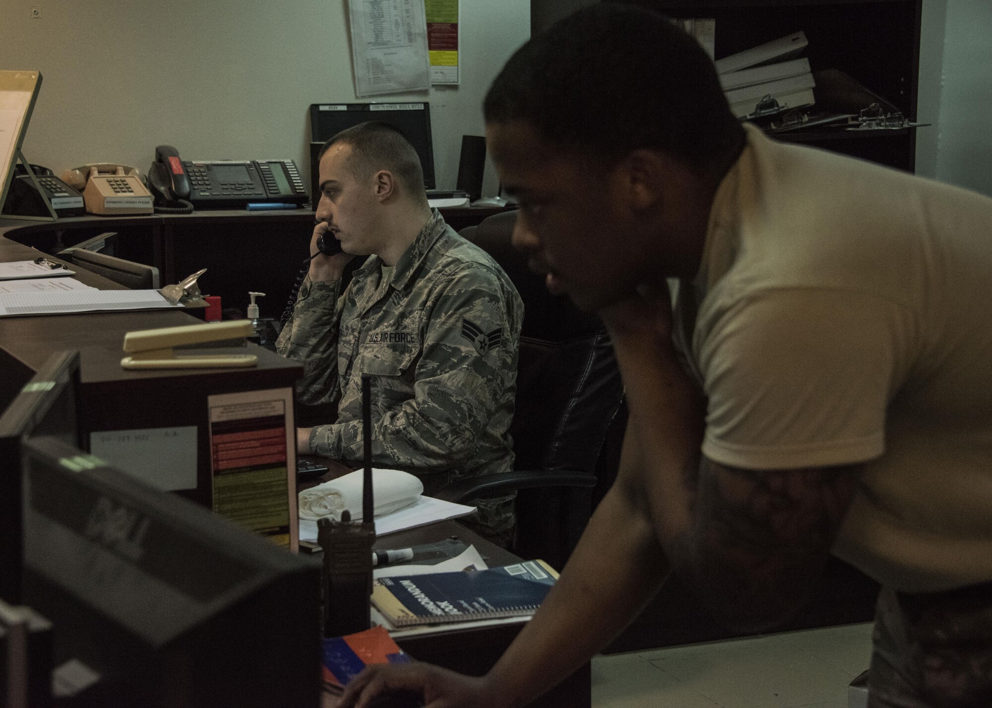 Airman 1st Class Derrik Bush and Senior Airman Jourdan Chaney, both airfield management specialists with the 386th Expeditionary Operations Support Squadron man the phones at the operations desk in an undisclosed location in Southwest Asia. A minimum of two airfield management specialists work around the clock manning the operations desk, processing flight plans, inputting prior permission requests for incoming aircraft and relaying restrictions and notices to airmen. (U.S. Air Force photo/Tech. Sgt. Jonathan Hehnly)  