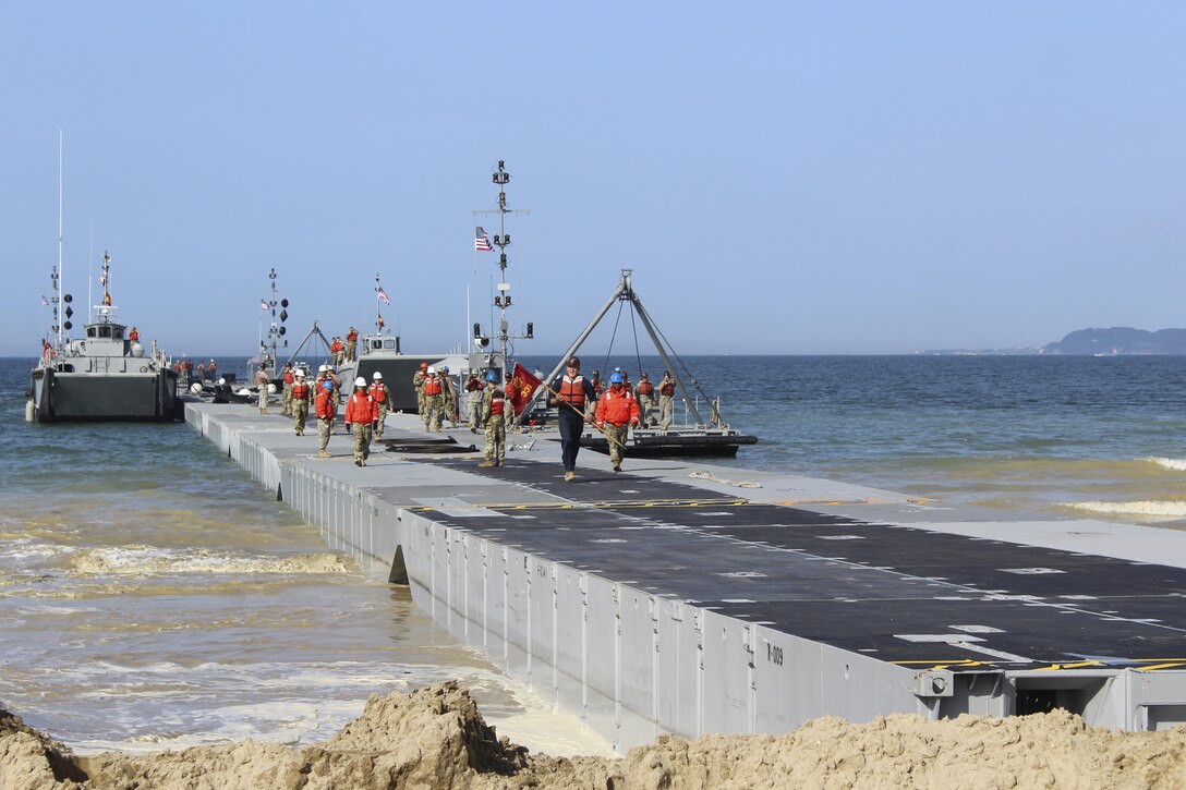 Members of the 7th Transportation Brigade (Expeditionary), 11th Transportation Battalion, 331st Causeway Company, "stab" the Trident pier during the Combined Joint Logistics Over-the-Shore 2017 exercise in Pohang, South Korea, April 7, 2017. The Trident pier is a 1200-ft long portable, floating platform that links offshore operations to land. Also known as a modular causeway system, this platform is built in the shape of a trident, then “stabbed” into the shore to offload warfighting equipment. (U.S. Army photo/Capt. Derrick Dixon) 