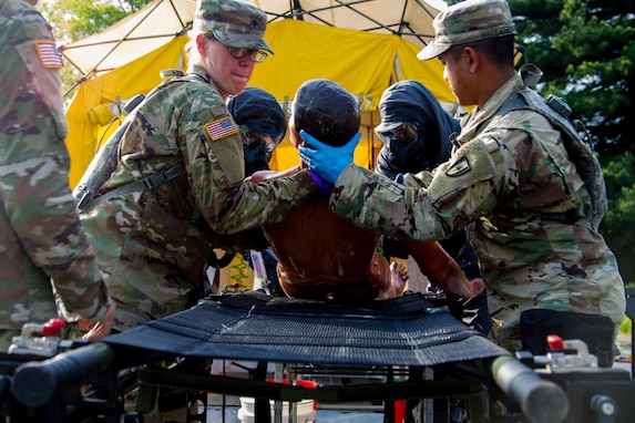 Spc. Megan Rowley (left) and Spc.  Kristopher Fernando medics assigned to the 602nd Area Support Medical Company located at Fort Bragg, N.C., move a scenario casualty from the decontamination area to a gurney for assessment April 29, 2017, as part of  Exercise Guardian Response at Muscatatuck Urban Training Center, Ind. Guardian Response is a multi-component training exercise run by the U.S. Army Reserve designed to validate more than 4,000 service members in Defense Support of Civil Authorities (DSCA) in the event of a Chemical, Biological, Radiological and Nuclear (CBRN) catastrophe. This year's exercise simulated an improvised nuclear device explosion with a source region electromagnetic pulse (SREMP) out to more than four miles. The 84th Training Command is the hosting organization for this exercise, with the training operations run by the 78th Training Division, headquartered in Joint Base McGuire-Dix-Lakehurst, New Jersey. (U.S. Army Reserve Photo by Maj. Adam Weece, 206th Broadcast Operations Detachment)