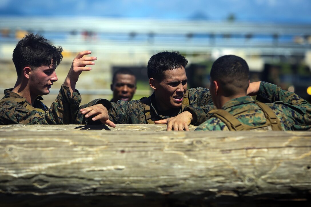 Marines encourage Cpl. Omar Perez to climb over a log during the obstacle course portion of a martial arts instructor course at Marine Corps Base Hawaii, May 1, 2017. Perez is an engineer equipment mechanic. Marine Corps photo by Cpl. Zachary Orr
