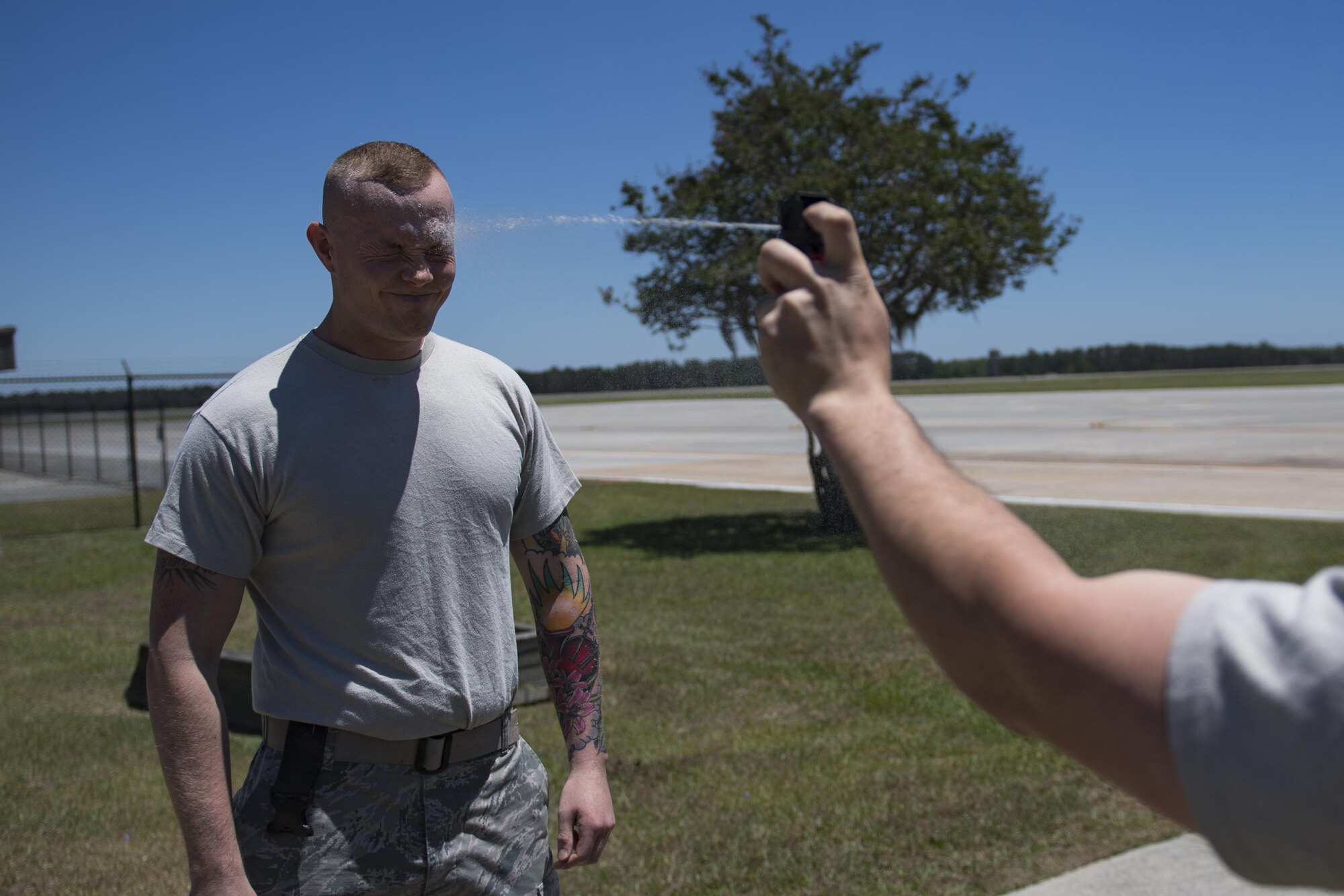 A unit trainer sprays Airman 1st Class Hunter Ogle, 23d Security Forces Squadron entry controller, in the face with oleoresin capsicum spray, also known as pepper spray, during an initial confidence course, May 2, 2017, at Moody Air Force Base, Ga. Airmen must complete a class then pass a physical confidence course while experiencing the effects of oleoresin capsicum spray to be qualified to carry the less-than-lethal tool. (Air Force photo by Airman 1st Class Daniel Snider)