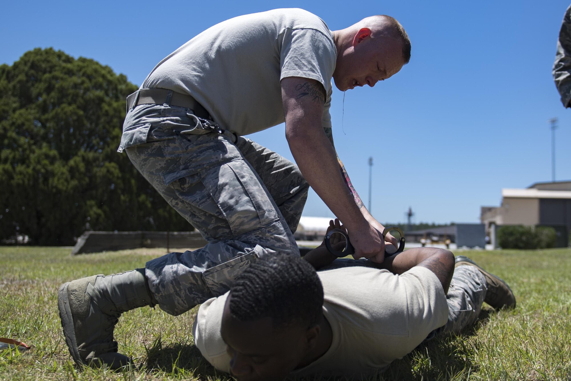 Airman 1st Class Hunter Ogle, 23d Security Forces Squadron entry controller, hand-cuffs Senior Airman Brandon Miles, Senior Airman Brandon Mile, 23d SFS unit trainer, after being sprayed in the face with oleoresin capsicum spray, also known as pepper spray, during an initial confidence course, May 2, 2017 at Moody Air Force Base, Ga. Airmen must complete a class then pass a physical confidence course while experiencing the effects of oleoresin capsicum spray to be qualified to carry the less-than-lethal tool. (Air Force photo by Airman 1st Class Daniel Snider)