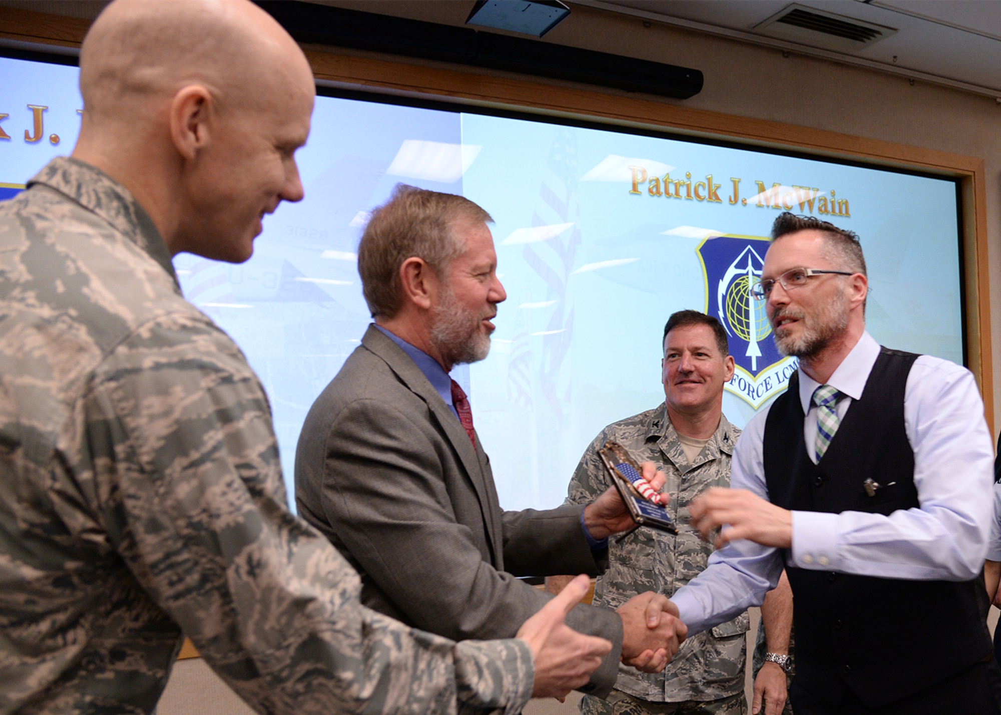 Patrick J. McWain, a lead security specialist for the Nuclear Command, Control and Communication Integration Directorate, is congratulated by Scott C. Hardiman, center, deputy director for NC3, Lt. Col. Kenneth Ferland, left, for the 66th Air Base Group, and Col. Dale VanDusen, for Battle Management, during the Team Hanscom Quarterly Awards Ceremony on base May 3. McWain, who captured the category two civilian of the quarter award, was one of 10 award recipients during the quarterly event. (U.S. Air Force photo by Linda LaBonte Britt)