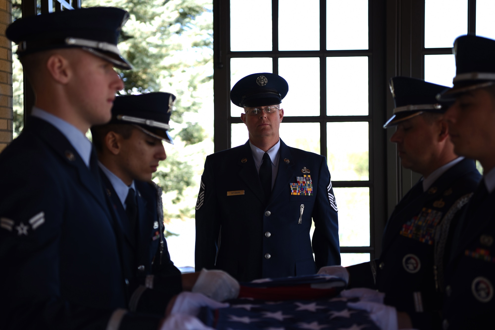 Senior Master Sgt. Brett Kitzman, 140th Maintenance Group aircraft armament systems superintendent, stands at attention while members of the Mile High Honor Guard fold the flag during a military funeral honor, Apr. 28, 2017, at Fort Logan National Cemetery, Colo. Kitzman, who worked with the deceased in the past, volunteered to participate in the service and to present to tri-fold flag to the next of kin. (U.S. Air Force photo by Airman 1st Class Holden S. Faul/ released)