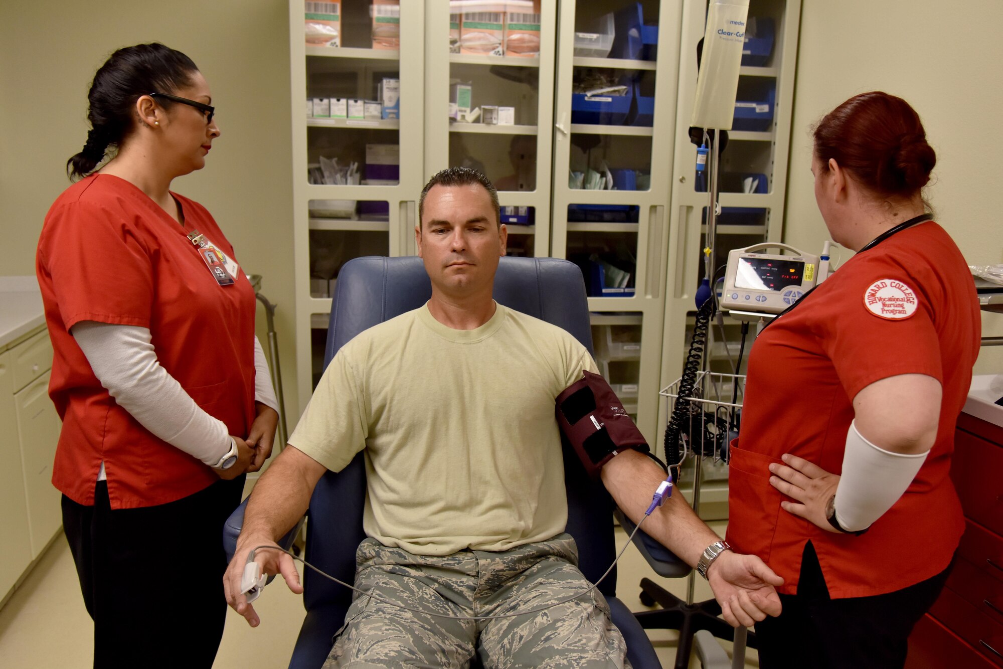 Dee Torres and Barbara Jermyn, Howard College nursing students, practice taking blood pressure and heart rate on Master Sgt. John Gregg, 17th Medical Operations Squadron superintendent, at the Ross Clinic on Goodfellow Air Force Base, Texas, May 2, 2017. Jermyn and Torres came to learn at the clinic as part of two-day clinical rotation partnership with Howard College. (U.S. Air Force photo by Staff Sgt. Joshua Edwards/Released)
