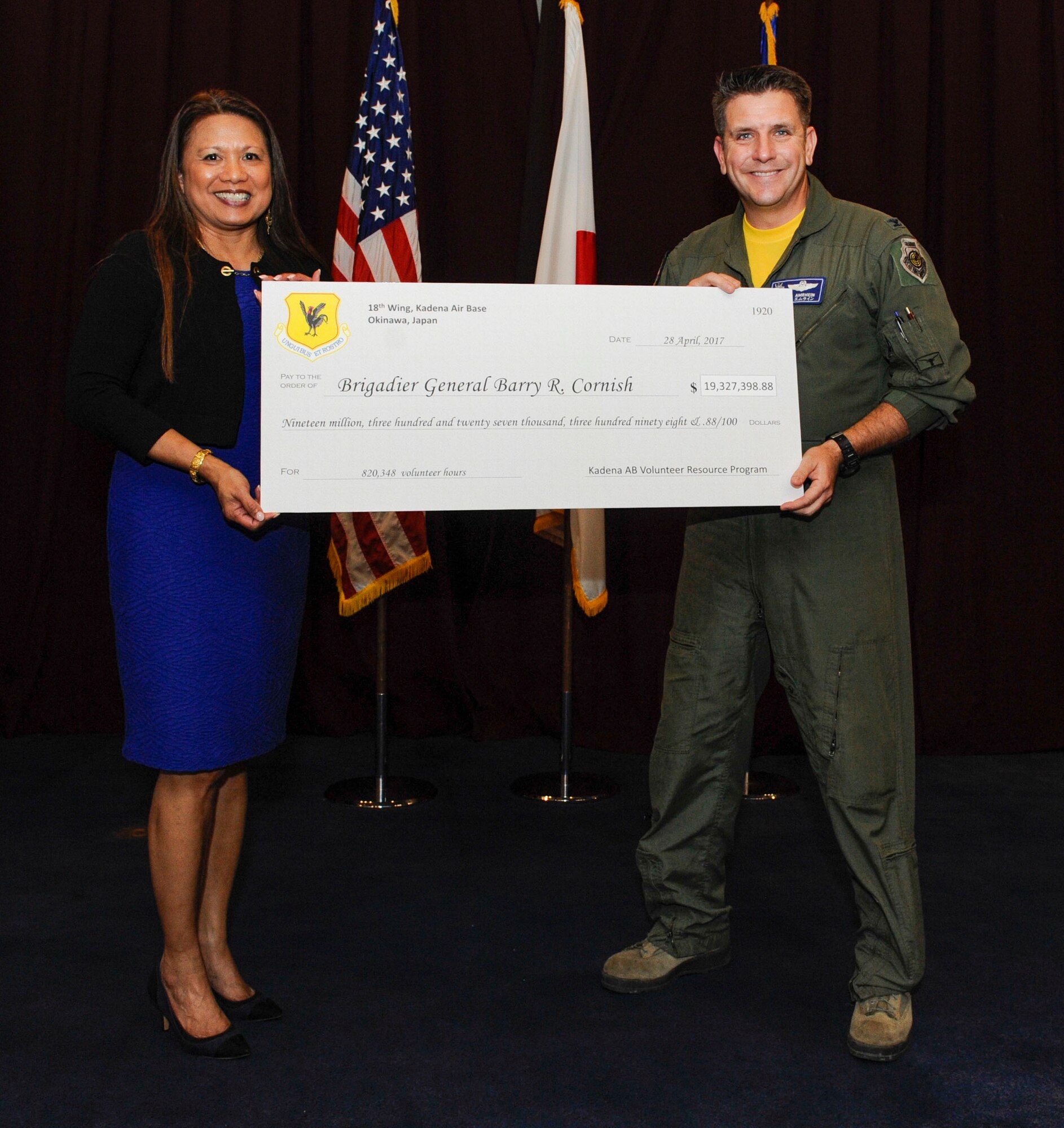 U.S. Air Force Col. Christopher Amrhein, 18th Wing vice commander, and Emiciosa Cox, 18th Force Support Squadron supervisory lead, hold a symbolic check from Kadena Volunteer Resource Program during the 18th Wing Annual Volunteer Recognition ceremony April 28, 2017, at Kadena Air Base, Japan. Team Kadena members contributed more than 820,000 volunteer hours to the base and local community over the past year. Thousands of volunteers from Kadena, including joint service members and civilians, saved the base more than $19 \million. (U.S. Air Force photo by Senior Airman Lynette M. Rolen)