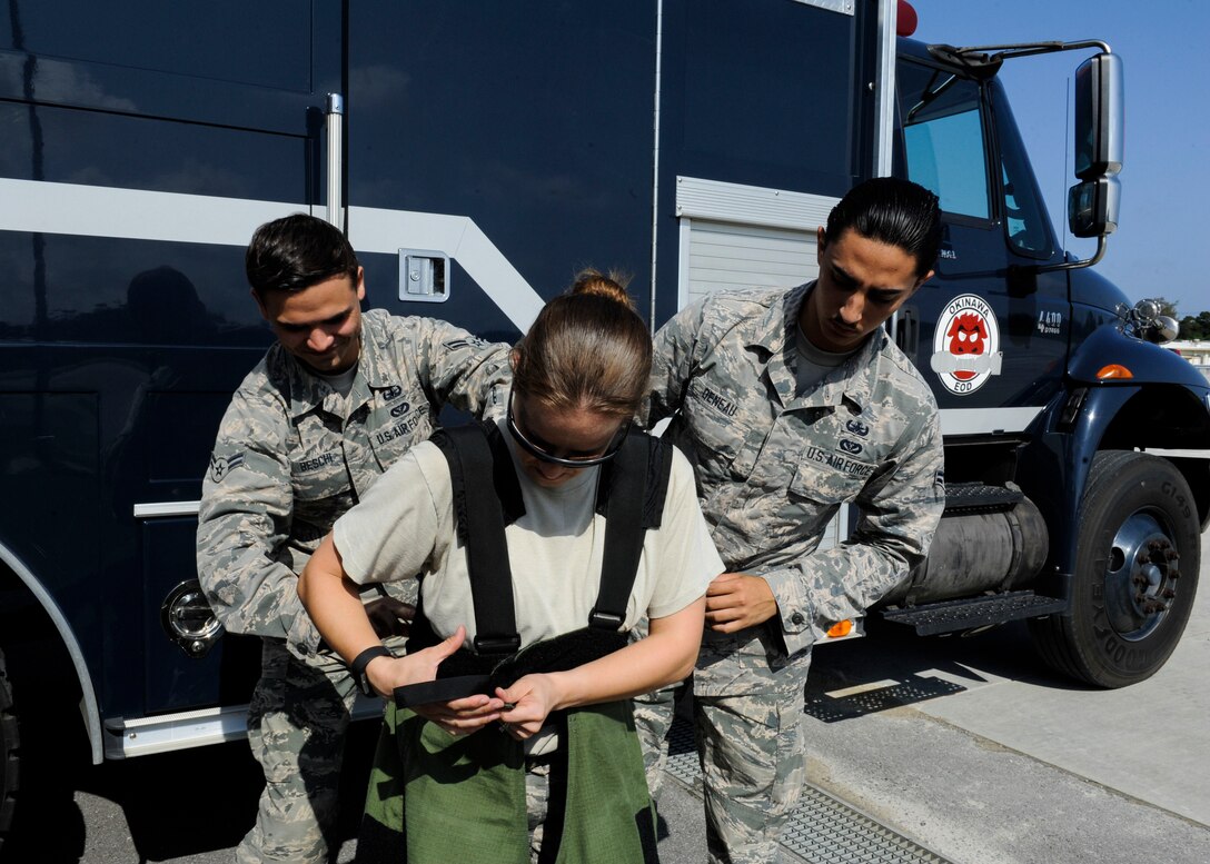 U.S. Air Force Airmen 1st Class Anthony Beschi and Quentin Deneau, 18th Civil Engineer Squadron Explosive Ordnance Disposal apprentices, assist Tech. Sgt. Rebecca Kimberling, 18th CES EOD supply NCO in charge, as she gets into an EOD bomb suit May 4, 2017, at Kadena Air Base, Japan. Explosive Ordnance Disposal response is made possible through team dynamics between NCOs and Airmen. (U.S. Air Force photo by Senior Airman Lynette M. Rolen)