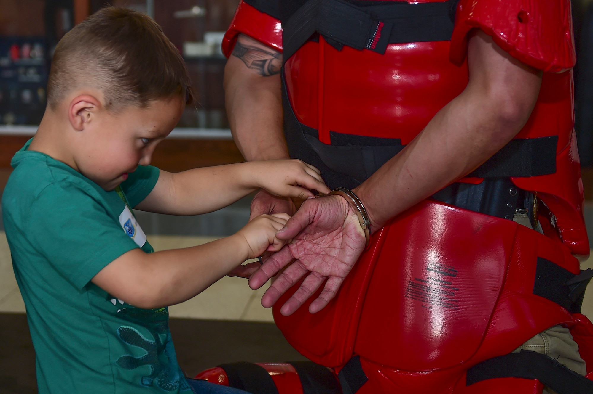 Kai, a Buckley Youth, practices using handcuffs on Special Agent Jason, 12th Field Investigations Squadron, on “Bring Our Daughters and Sons to Work Day”, April 27, 2017, on Buckley Air Force Base, Colo. The children spent the day learning investigation skills, including forensics and arresting techniques. (U.S. Air Force photo by Airman Jacob Deatherage/Released)
