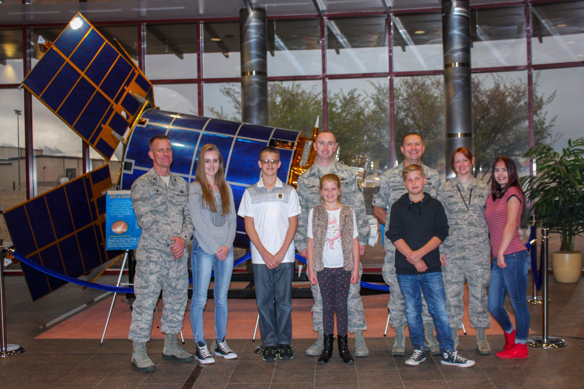 Team Buckley space operators and their families pose in front of a satellite in the Mission Control Center April 27, 2017, on Buckley Air Force Base, Colo. The children received a tour of their parent’s work centers and one of the radomes. (Courtesy photo)