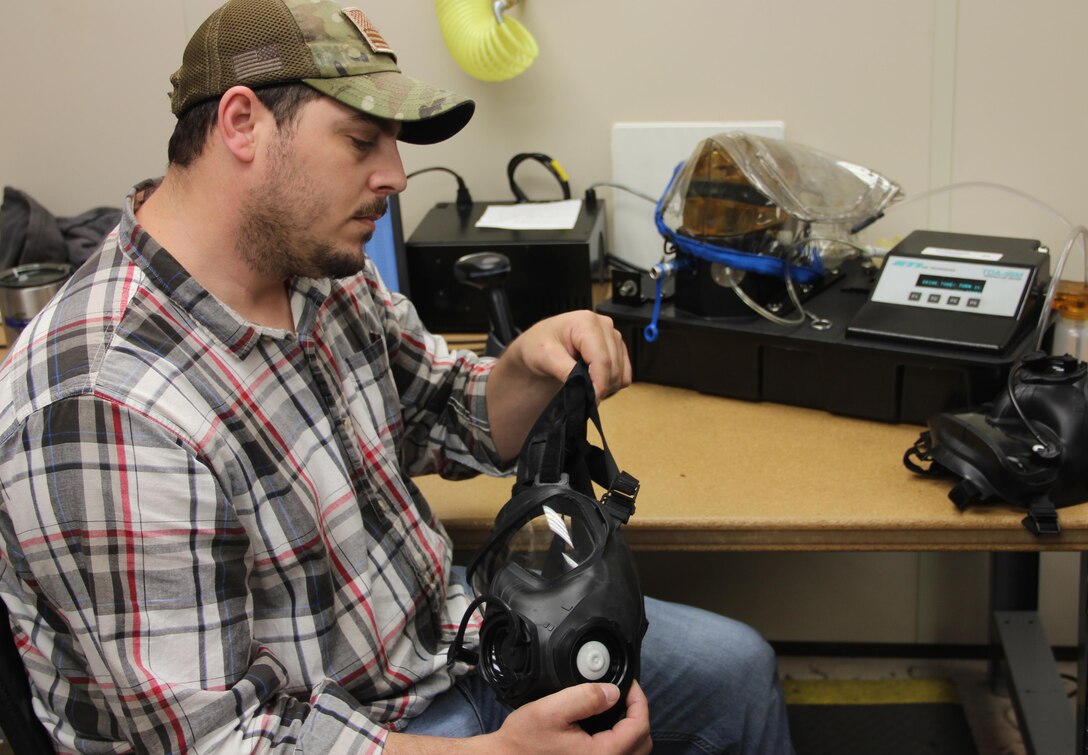 Justin Rayner conducts a visual inspection of an M50 mask after it comes out of the drying room. Rayner is a member of a small team of 13 that breaks down, inspects, repairs, cleans, sanitizes and tests about 8,000 masks each month for the Air Force. (U.S. Air Force photo/Rodney Whaley)