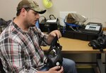 Justin Rayner conducts a visual inspection of an M50 mask after it comes out of the drying room. Rayner is a member of a small team of 13 that breaks down, inspects, repairs, cleans, sanitizes and tests about 8,000 masks each month for the Air Force. (U.S. Air Force photo/Rodney Whaley)