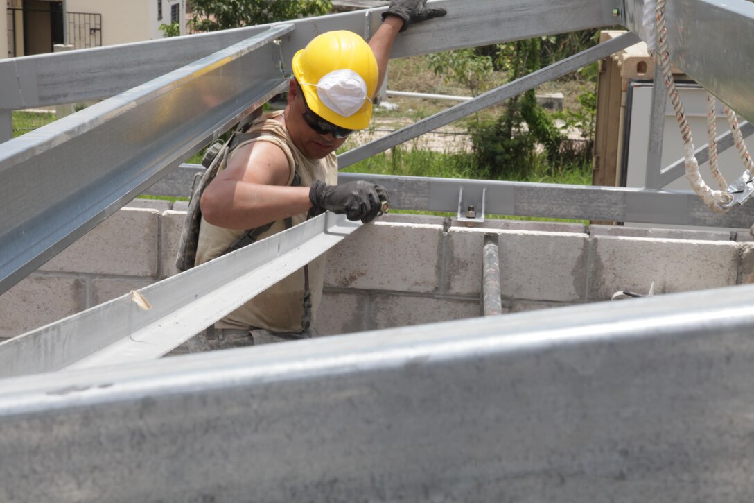 A U.S. Soldier, with the 372nd Engineer Company, positions a beam on the roof at the Ladyville, Belize Medical Clinic construction site, during Beyond the Horizon 2017, May 1st, 2017. Beyond the Horizon is a U.S. Southern Command-sponsored, Army South-led exercise designed to provide humanitarian and engineering services to communities in need, demonstrating U.S. support for Belize. (U.S. Army photo by Spc. Gary Silverman)