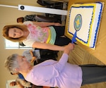 Louise Nazario (left) and Jennifer Haigh (right), civilian employees at Navy Medicine Education, Training and Logistics Command, or NMETLC, cut a ceremonial cake following the establishment of the Navy Medicine Civilian Corps. NMETLC was one of many Navy commands to watch the live stream of the official ceremony from Bureau of Medicine and Surgery headquarters in Washington, D.C.