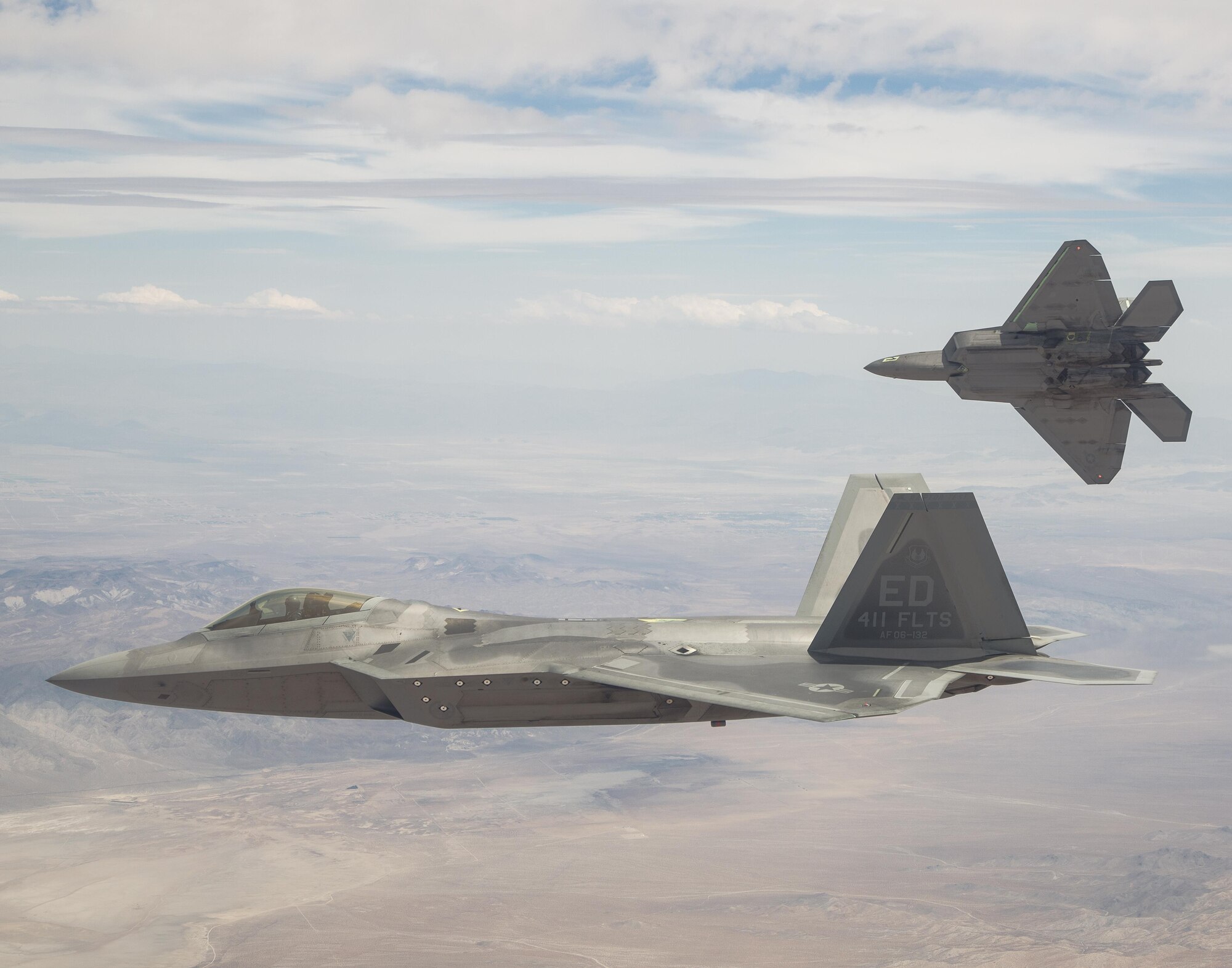 Two F-22 Raptors from the 411th Flight Test Squadron fly above the California High Desert in this photo.  Developmental tests of air-to-air missiles against an aerial target were completed April 18 at the Utah Test and Training Range as part of a major capability upgrade. (Courtesy photo by Chad Bellay/Lockheed Martin)