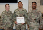 Staff Sgt. Nissan N. Armas (center) is congratulated by Col. Tayna Peacock (left), Vice Provost of Academic Affairs, Directorate of Training and Academic Affairs, U.S. Army Medical Department Center & School, and Sgt. Maj. Christopher R. Marshall (right), Sergeant Major, Directorate of Training and Academic Affairs, AMEDDC&S.