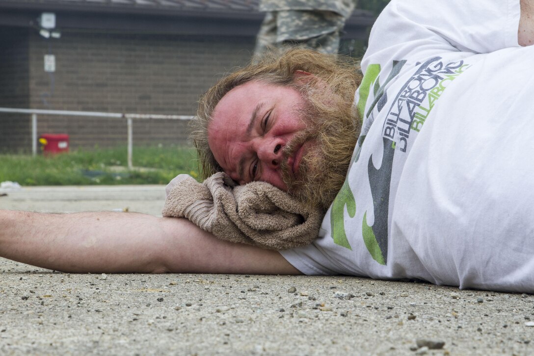 Civilian role player Derek Pastrick, a Columbus, Ind., resident, lies on the ground awaiting help following a mock nuclear disaster at the Muscatatuck Urban Training Center, April 28, 2017. The U.S. Army Reserve’s Guardian Response 2017 is a multi-component training exercise designed to validate more than 4,000 service members in Defense Support of Civil Authorities in the event of a Chemical, Biological, Radiological and Nuclear catastrophe. This year's exercise simulated an improvised nuclear device explosion with a source region electromagnetic pulse out to more than four miles. The 84th Training Command hosted this exercise and the 78th Training Division, headquartered in Joint Base McGuire-Dix-Lakehurst, New Jersey, conducted the training operations. (U.S. Army Reserve photo by Sgt. Beth Raney, 343rd Mobile Public Affairs Detachment)
