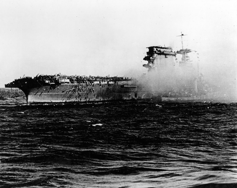 A destroyer pulls alongside the aircraft carrier USS Lexington as the carrier is abandoned during the afternoon of May 8, 1942. Note crewmen sliding down lines on Lexington's starboard quarter. Navy photo
