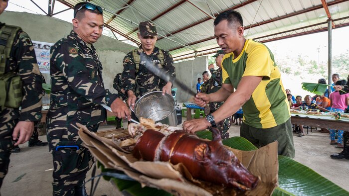 Philippine Soldiers prepare a roasted pig for a Boodle Fight at a disaster preparedness symposium during Balikatan 2017 in Ormoc City, Leyte, May 2, 2017.  A Boodle Fight is a communal meal and Philippine military tradition to symbolize unity and camaraderie. The Armed Forces of the Philippines along with representatives from Japan Self-Defense Force, Australian Defence Force, and U.S. military worked with a local barangay to improve health conditions and disaster preparedness. Balikatan is an annual U.S.-Philippine bilateral military exercise focused on a variety of missions, including humanitarian assistance and disaster relief, counterterrorism, and other combined military operations. 