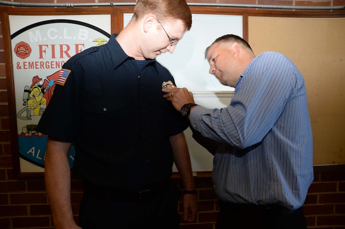 Jonathan Kirkman (left) joins Marine Corps Logistics Base Albany’s firefighters’ team in a ceremony, here, May 3. Jonathan's father, Phillip Kirkman, director, Retail Integration Division, Marine Corps Logistics Command, pinned on his son’s badge during the event. According to Philip Partin, fire chief, Jonathan is the first entry-level trainee to graduate from the Department of Defense Fire Academy at Goodfellow Air Force Base, San Angelo, Texas, in the history of the base.