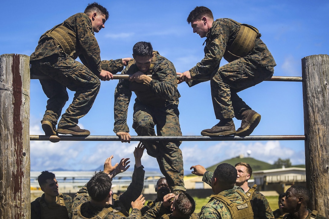 Marines Corps Cpl. Omar Perez receives help from fellow Marines over a double bar during the obstacle course portion of the Martial Arts Instructor Course at Marine Corps Base Hawaii, May 1, 2017. The Marines are assigned to the 11th Marine Expeditionary Unit. Marine Corps photo by Cpl. Zachary Orr