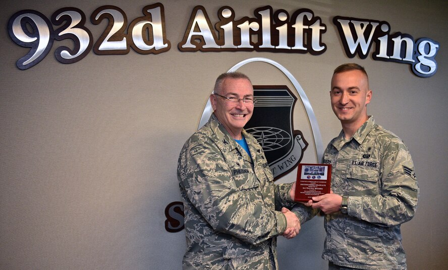 Col. Jonathan M. Philebaum, commander, 932nd Airlift Wing, takes time during the Wing Review meeting May 5, 2017 to honor and present Senior Airman Travis J. Biggers, with the Distinguished Graduate plague Biggers earned for his academic excellence while attending the Chief Master Sergeant of the Air Force Bud Andrews Airman Leadership School Scott Air Force Base, Illinois. "The school was challenging but I learned a lot and gained some tools," said Biggers.  (U.S. Air Force photo by Christopher Parr)