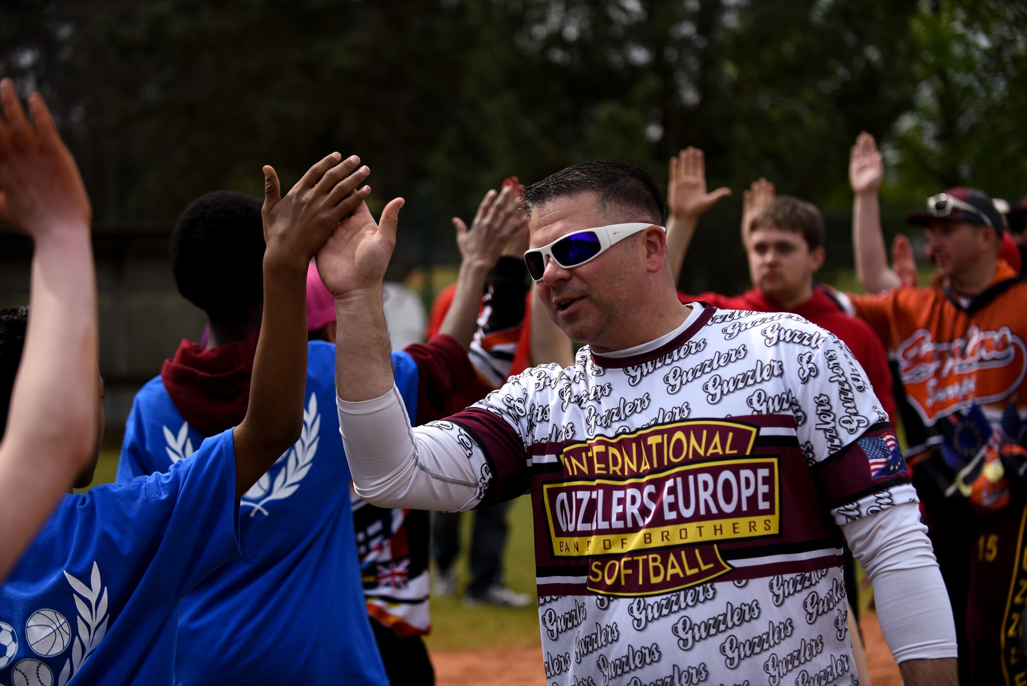 U.S. Army Chief Warrant Officer Patrick Waltman, European Guzzlers softball player, high fives students after the Adaptive Sports softball game at Donnelly Park on Ramstein Air Base, Germany, May 4, 2017. As part of tradition, opposing teams will slap hands and exchange the words “good game” to show respect and good sportsmanship. (U.S. Air Force photo by Senior Airman Devin Boyer/Released)