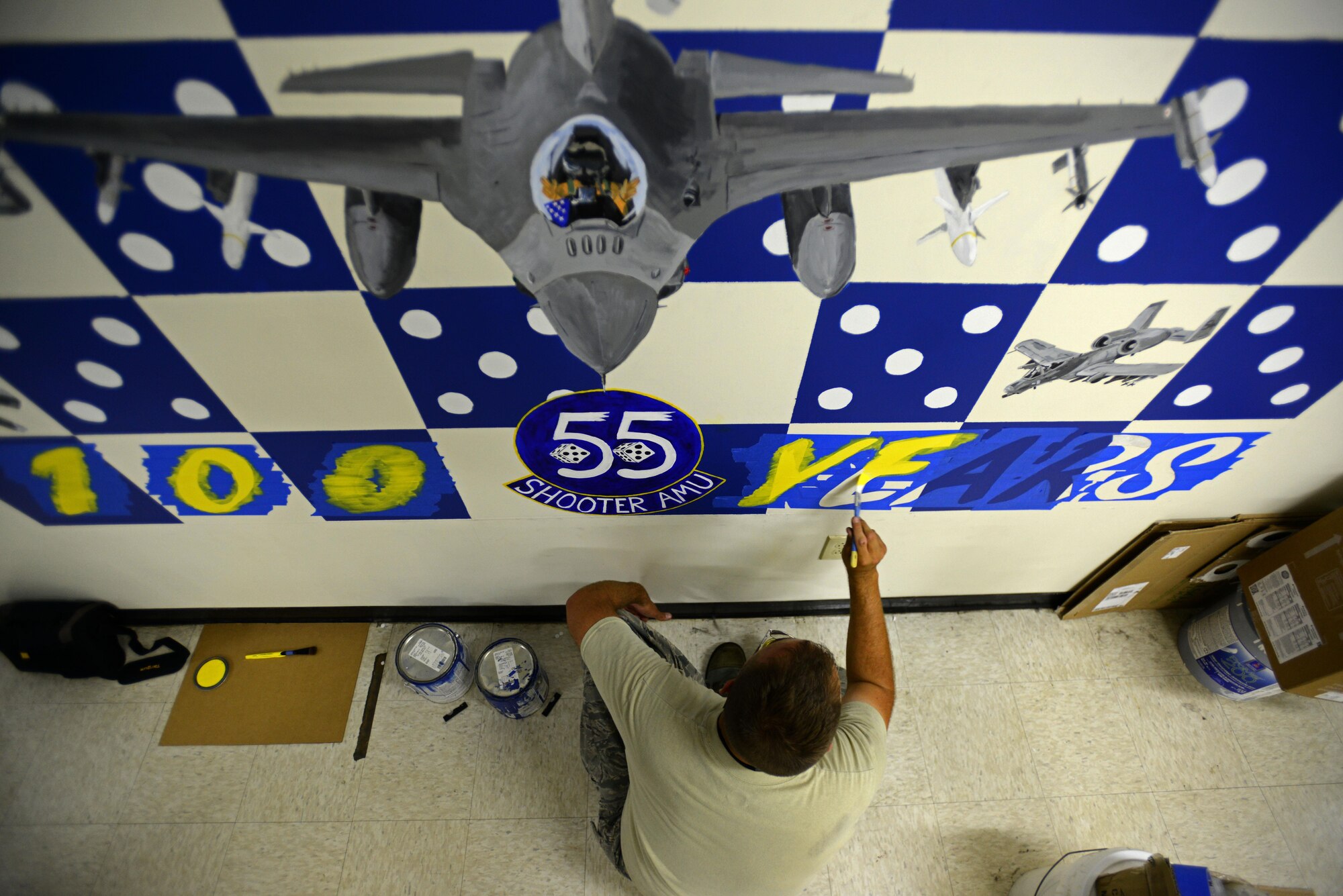 U.S. Air Force Tech. Sgt. Brian Barnes, 20 Aircraft Maintenance Squadron, 55th Aircraft Maintenance Unit (AMU) tactical aircraft maintainer, applies the first coat of paint to the ‘100 Years’ portion of a mural at the 55th AMU building at Shaw Air Force Base, S.C., April 24, 2017. The mural was designed to showcase the history and achievements of the 55th Fighter Squadron across 100 years. (U.S. Air Force photo by Senior Airman Kelsey Tucker)