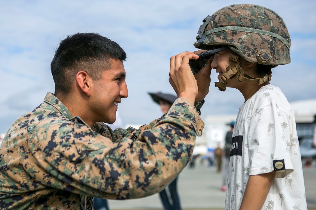 A Marine places sunglasses on a Japanese child during the 41st Japan Maritime Self-Defense Force – Marine Corps Air Station Iwakuni Friendship Day at the air station in Japan, May 5, 2017. Marine Corps photo by Lance Cpl. Tiana Boyd