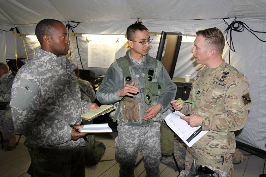 Capt. Alphonso Williams, S1 of the 457th Transportation Battalion, and Capt. Bach Dang, battalion executive officer, discuss the operations order production process with Observer Controller/Trainer Capt. Scott Dyer of 1st Brigade, Great Lakes Training Division, 75th Training Command, during a break from instruction on the Military Decision Making Process. During the "warm start" of WAREX 86-17-02 at Ft. McCoy, Wisconsin, participating units are developing the operations order to be used in the exercise using the MDMP, while receiving instruction on the process.