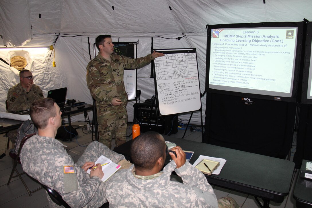 Capt. Jason Stoterau, of Orland Park, Illinois, teaches the Mission Analysis step of the Military Decision Making Process to the command team of the 457th Transportation Battalion at the battalion's tactical command post. Stoterau serves as an observer controller/trainer with 1st Brigade, Great Lakes Training Division, 75th Training Command, during the ongoing WAREX 86-17-02 at Ft. McCoy, Wisconsin.